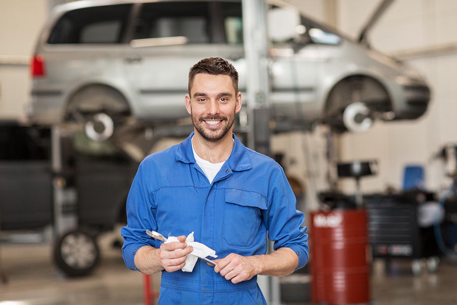 Specialized Business Insurance - Man in Blue Coveralls Holds a Wrench, Standing in an Auto Repair Shop